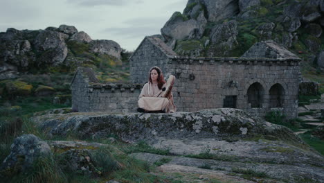 Mujer-Espiritual-Tocando-Pacíficamente-Un-Tambor-Chamánico-En-Una-Hermosa-Pista-De-Pueblo-Medieval-En-Plano-General