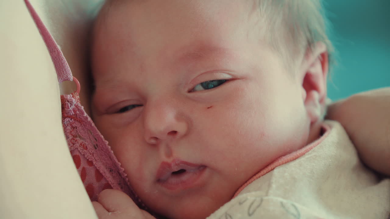 귀여운 갓난 아기가 엄마 품에 안겨 잠이 든다