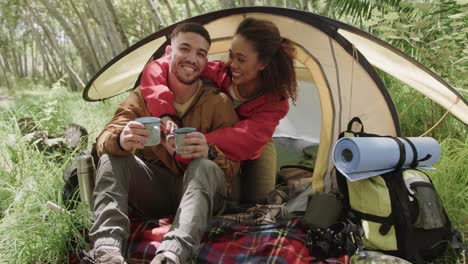 portrait of happy african american couple camping, drinking coffee in forest, slow motion