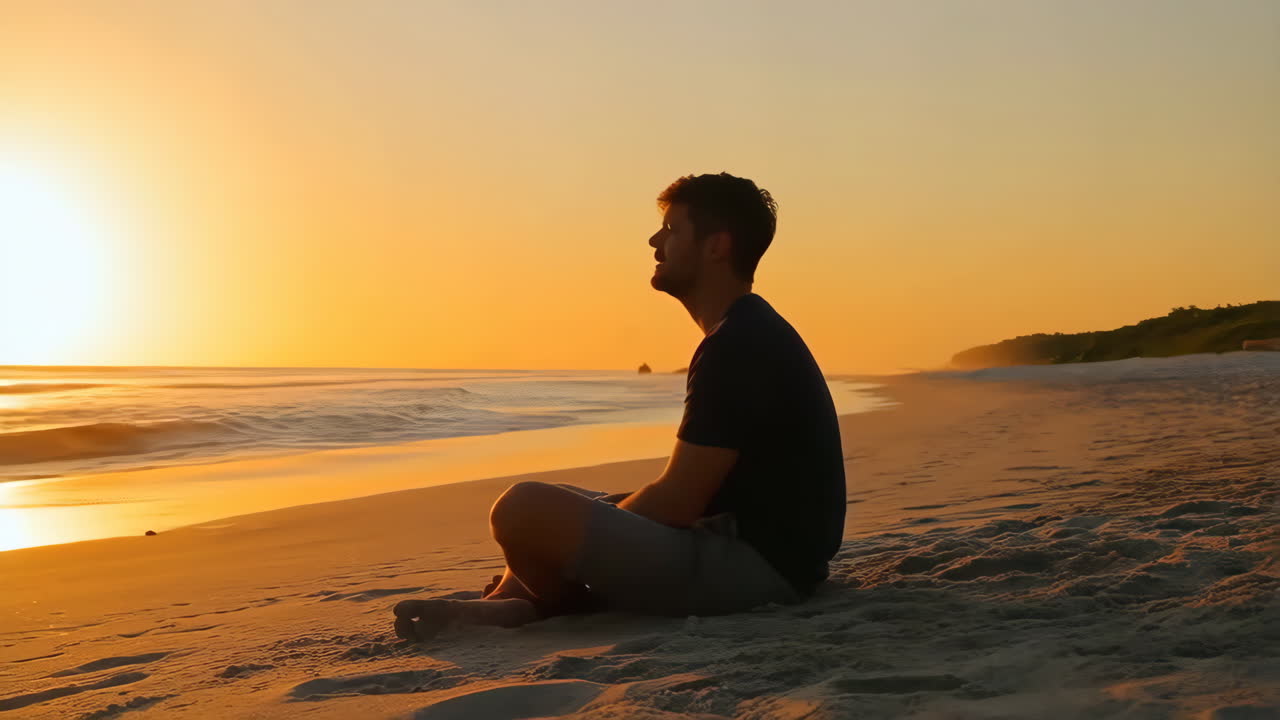 Man meditating on a beach at sunset