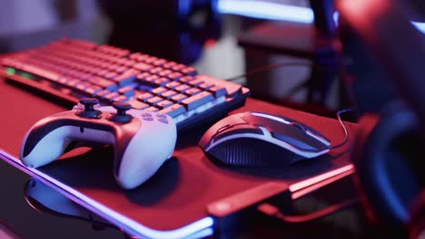 Video-of-computer-keyboard-and-gaming-equipment-on-desk-with-copy-space-on-neon-background