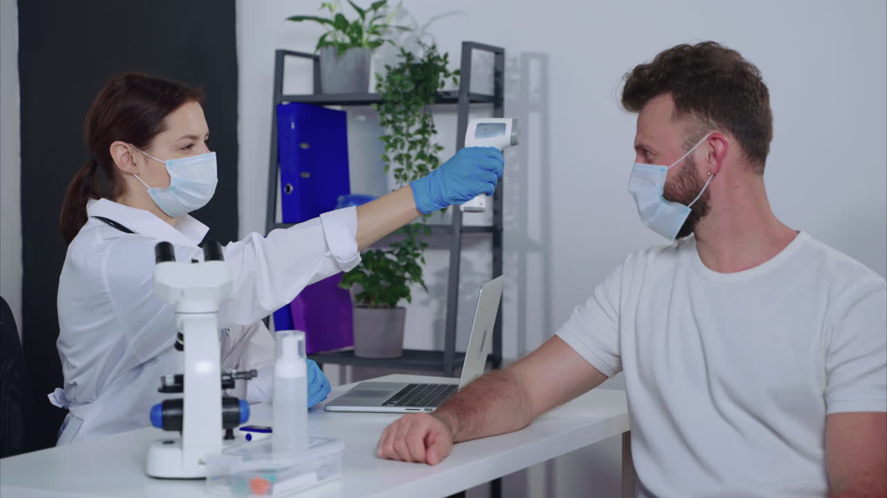 médico comprobando la temperatura del paciente en una clínica