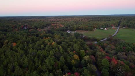 una panorámica larga de 30 segundos sobre un largo camino rural y un río en maine durante el comienzo de la temporada de otoño