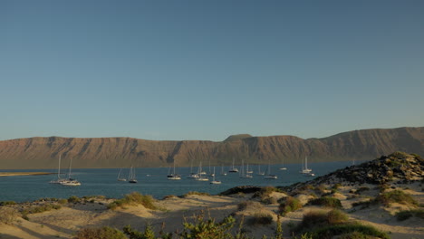 Anchored-sailboats-at-a-bay-in-La-Graciosa,-Lanzarote-on-a-cloudless-day