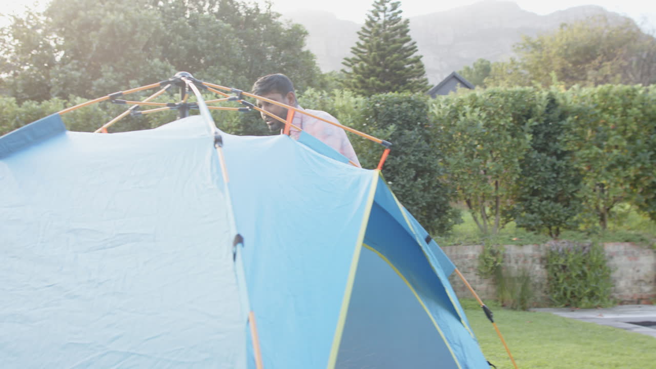 Setting up tent, Indian father and son enjoying outdoor camping together