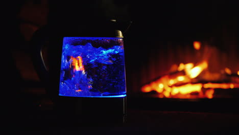 water boils in a backlit electric kettle a fire in the background burns in the background