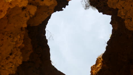 the roof of a cave has eroded away leaving a large hole stretching up to the surface above