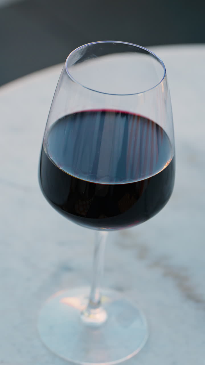 Primo piano di un bicchiere di vino rosso su un tavolo in una terrazza. Verticale