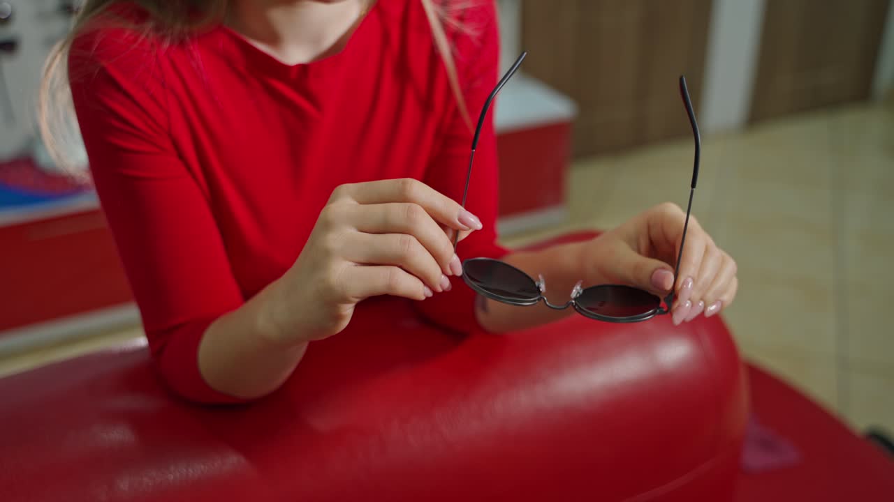Woman buying sunglasses in shop. Close up of woman in optician store holding stylish sunglasses
