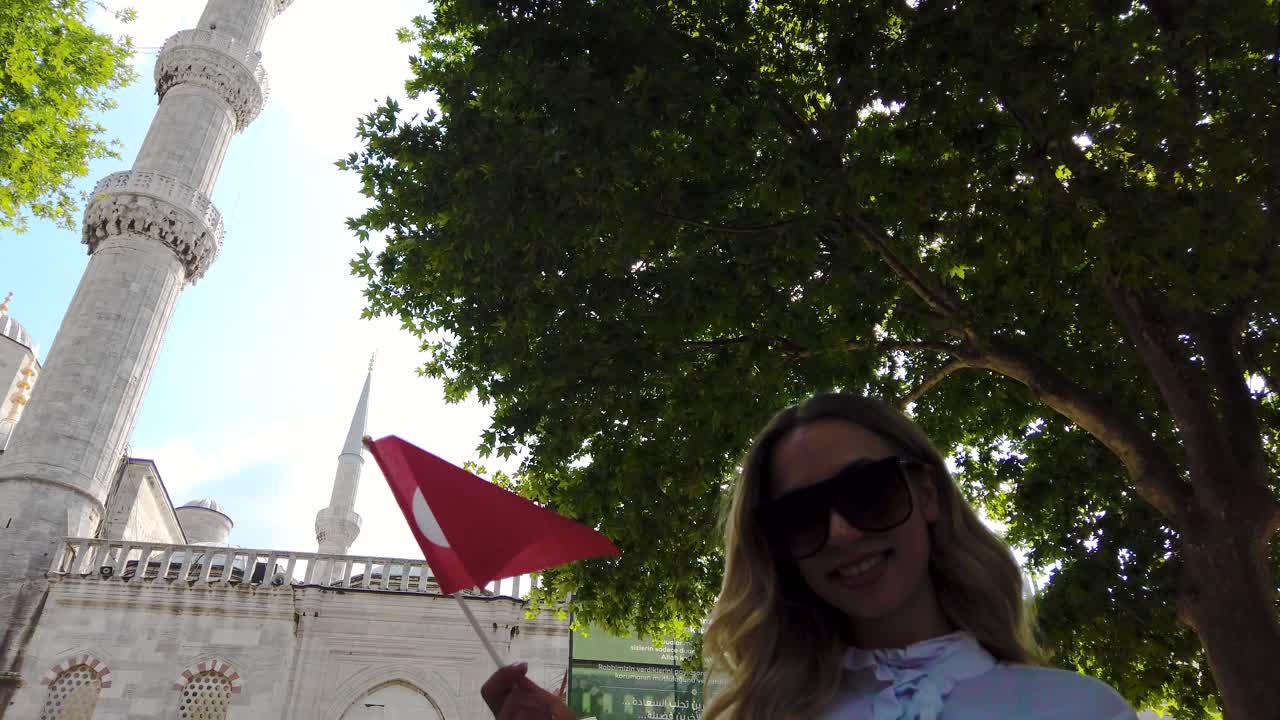 Jolie jeune femme en chemise agitant le drapeau turc avec vue sur la Mosquée Sultan Ahmet à Istanbul, Turquie.