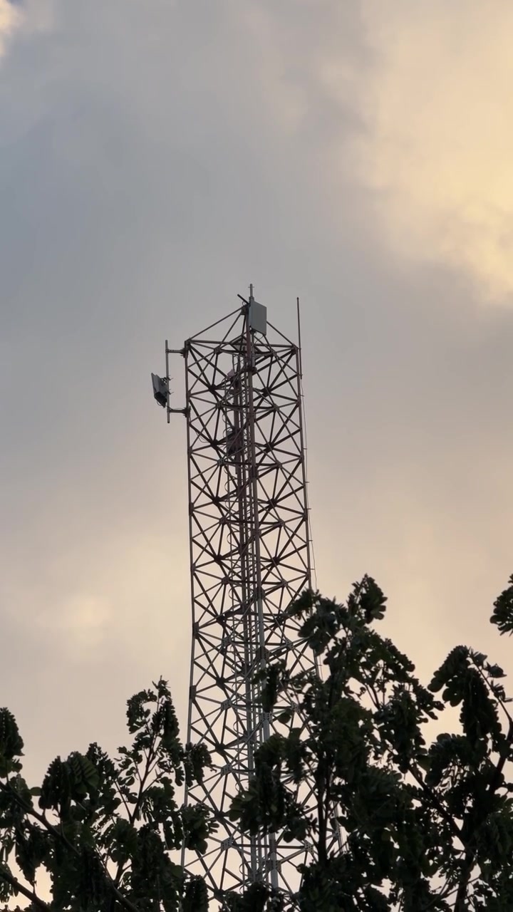 Torre di comunicazione contro cielo nuvoloso al tramonto