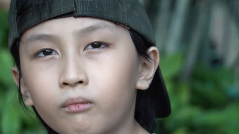 southeast asian boy looking cute and cool in slow motion close up out doors looking into the camera