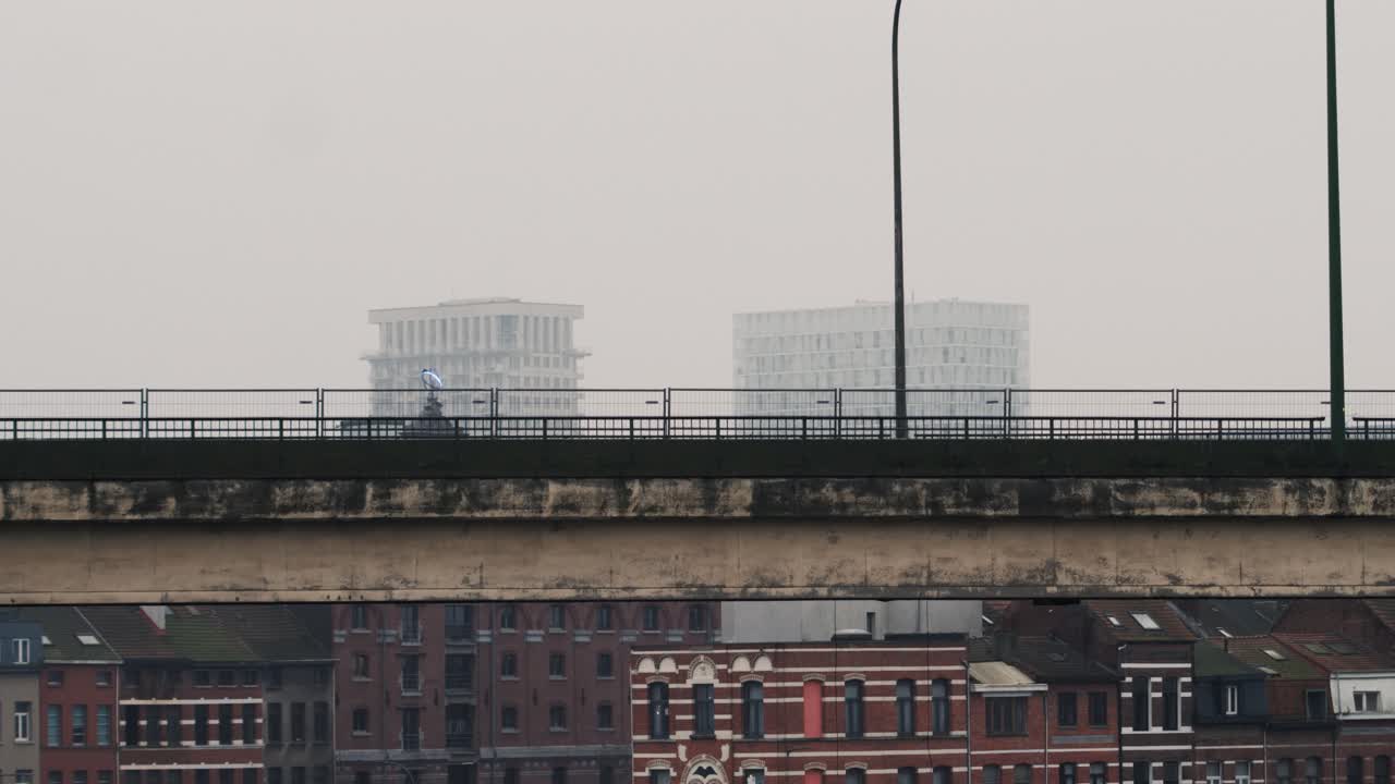 Busy city flyover captured with cars in motion against a backdrop of contrasting historical and modern architectures under a foggy sky, highlighting urban dynamics