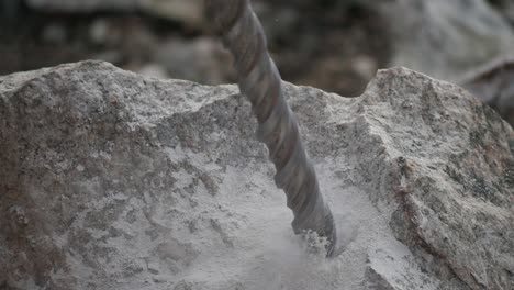 close up of a driller digging a hole into a rock producing smoke and sand in slow motion