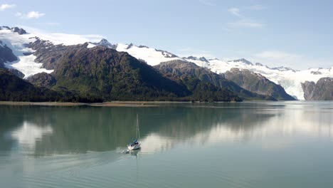 lancha motora navegando en aguas tranquilas con montañas nevadas a lo lejos, alaska, ee.uu. - aérea, estática