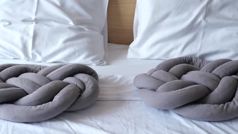 grey knotted pillows on a white bed