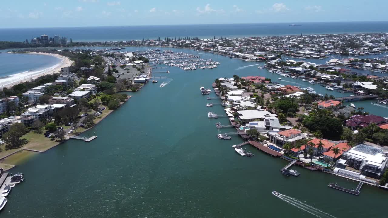 4K Drone footage of a large boat harbour near a sandy beach and expensive private homes