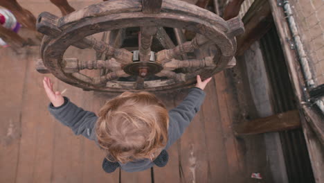 young child playing with a pirate ship wheel - imagination playing make believe