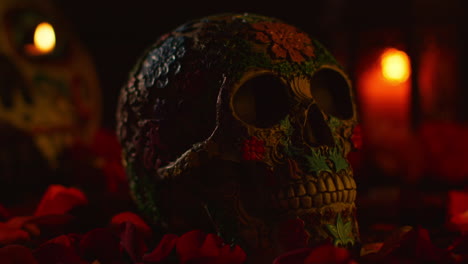 close up on still life of decorated skull surrounded by candles and flower petals celebrating mexican holiday of dia de muertos or day of the dead