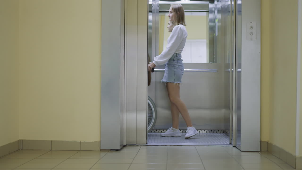 젊은 여성이 현대 엘리베이터의 문을 닫기 위해 버튼을 누릅니다.