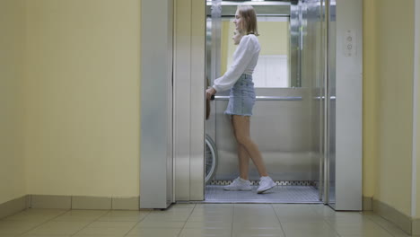 Young-woman-pushes-button-to-close-door-of-modern-elevator