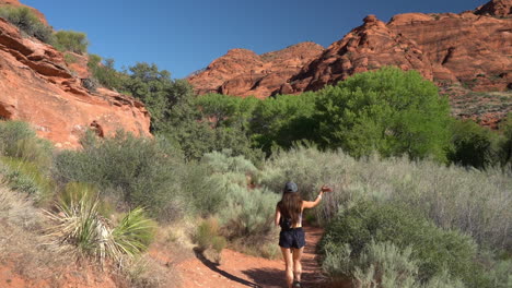 Young-Female-in-Desert-Wilderness-on-Hiking-Trail-Under-Red-Rock-Sandstone-Hills-Full-Frame-Slow-Motion