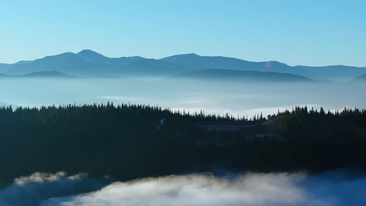 Misty Juniper Pass Colorado with peaks emerging through clouds in soft sunlight