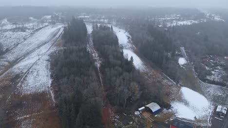 Erster-Kleiner-Schnee-Am-Berghang-Des-Skigebiets,-Luftaufnahme,-Nebliger-Tag