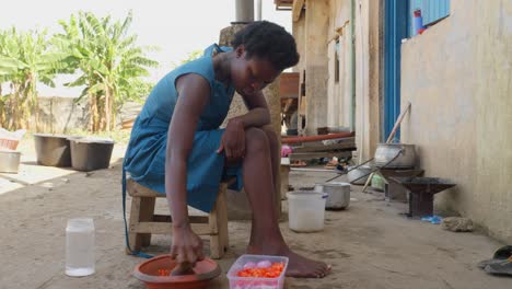 grinding vegetables to prepare stews that perfectly accompany banku, a yeasted flour dough ball, a typical ghanaian dish