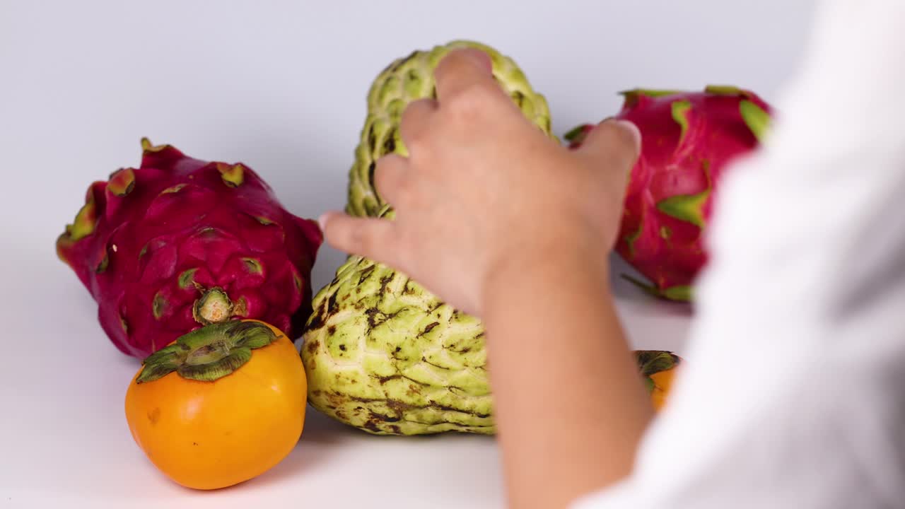 Mani che selezionano frutti da un assortimento colorato