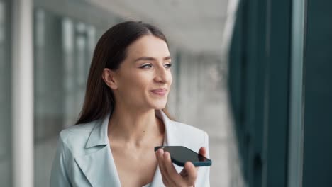 Portrait-of-a-beautiful-girl-in-a-jacket-talking-in-a-voice-with-a-smartphone