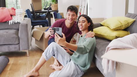 Feliz-Pareja-Masculina-Diversa-Mudándose-De-Casa,-Tomando-Café,-Tomándose-Selfie-Usando-Un-Teléfono-Inteligente