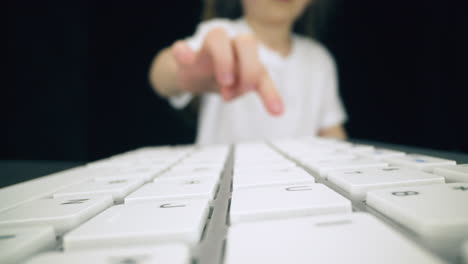 girl in white t-shirt presses keys on computer keyboard