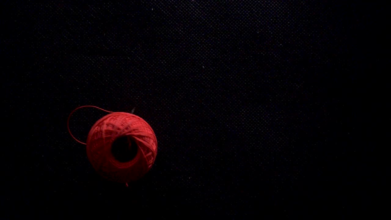 컬러 스레드 공은 느린 동작으로 떨어집니다. 검은 바탕은 정적입니다.