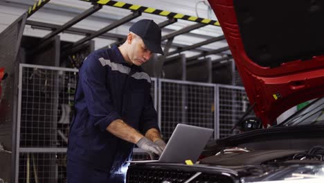 auto mechanic uses a laptop while conducting diagnostics test