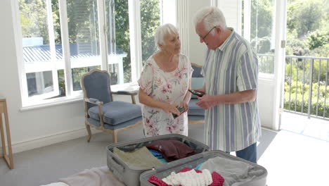 Pareja-Caucásica-Mayor-Empacando-Maleta-En-El-Dormitorio-En-Casa,-Cámara-Lenta