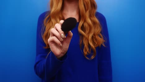 hermosa joven pelirroja de jengibre con suéter azul posando aislada en el fondo de color azul en el estudio