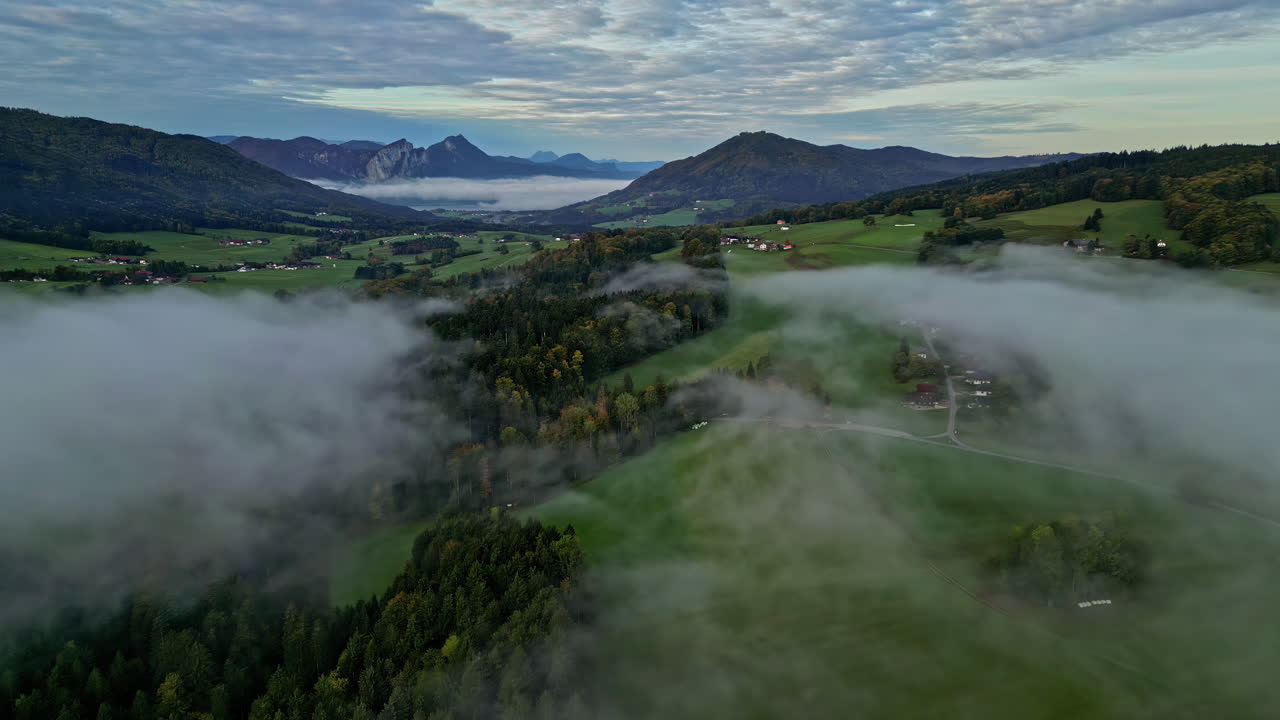 drone aéreo disparado sobre nubes blancas que pasa sobre una ciudad montañosa a lo largo del valle montañoso cubierto de vegetación verde durante la noche