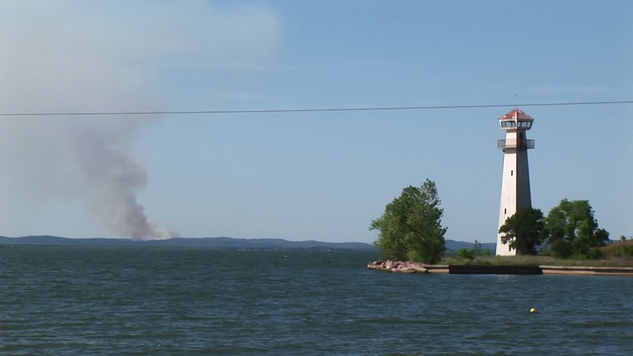수평선 위로 연기가 피어오르는 등대의 미디엄샷