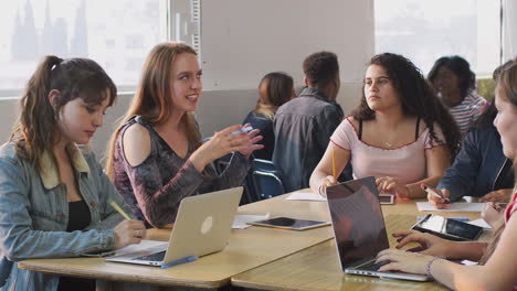 Grupo-De-Estudiantes-Universitarias-Sentadas-En-Un-Escritorio-Usando-Computadoras-Portátiles-Colaborando-Juntas-En-Un-Proyecto