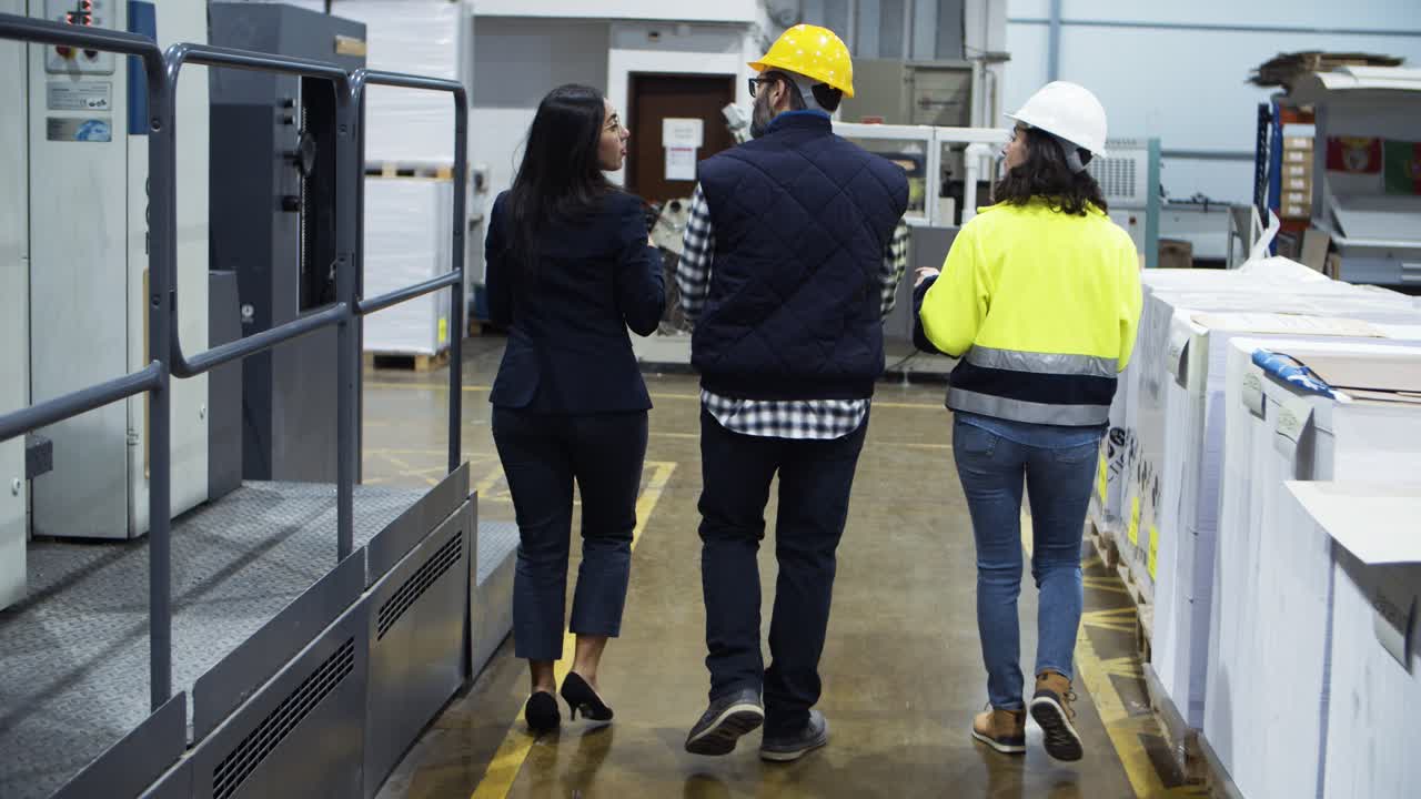 Vista trasera de gerente de proyecto mostrando la fábrica a los técnicos