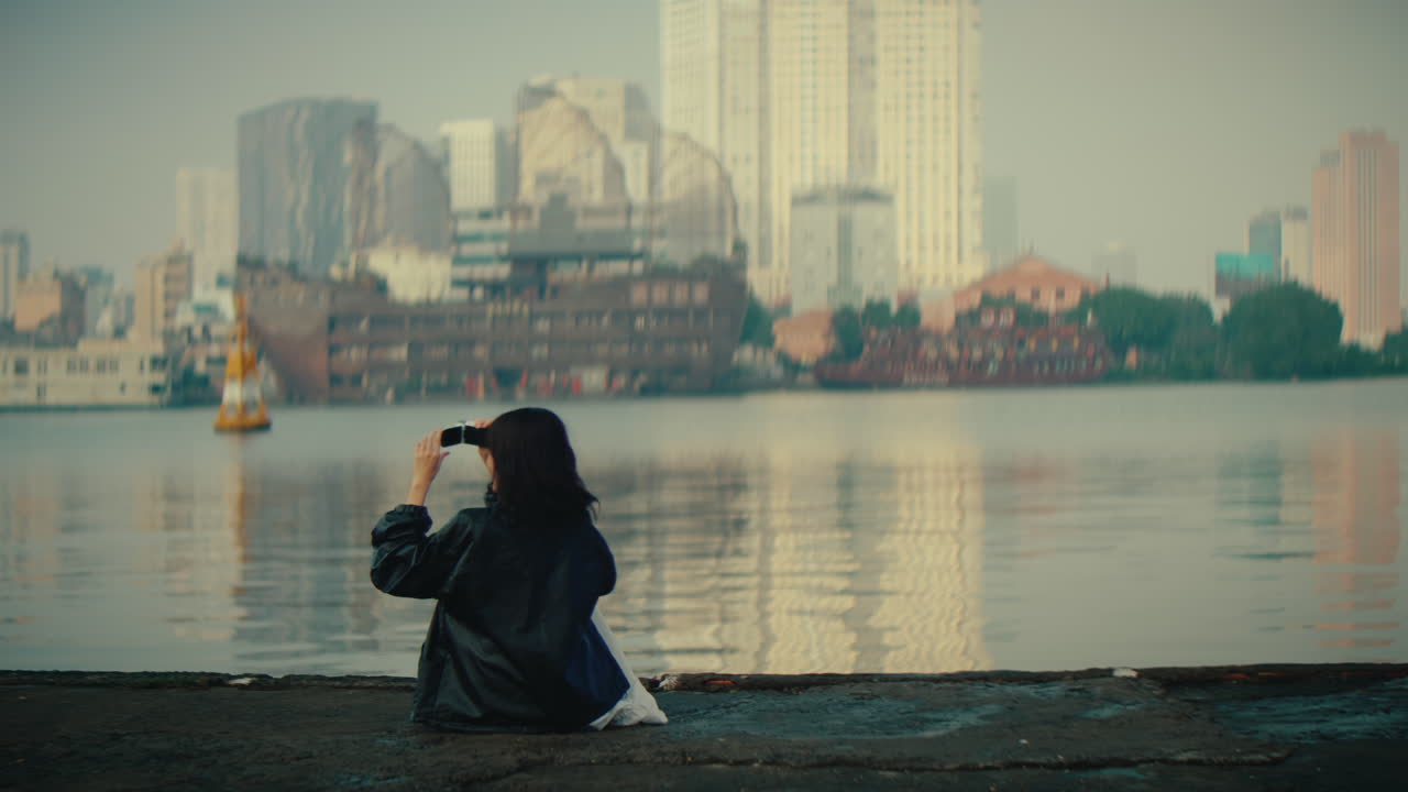 Woman taking photo of cityscape at riverside