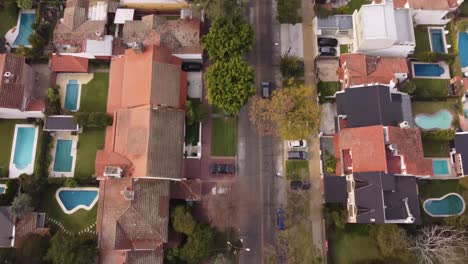 Aerial-tracking-top-down-pov-over-car-driving-along-Parana-Avenue-in-Vicente-Lopez-residential-area-of-Buenos-Aires,-Argentina