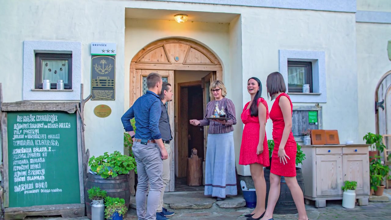 Eine Gruppe von Gästen, die zu einem Restaurant gehen, wird von einer Kellnerin an der Tür begrüßt.