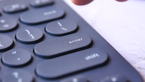 el dedo presionando la tecla de entrada en un teclado oscuro