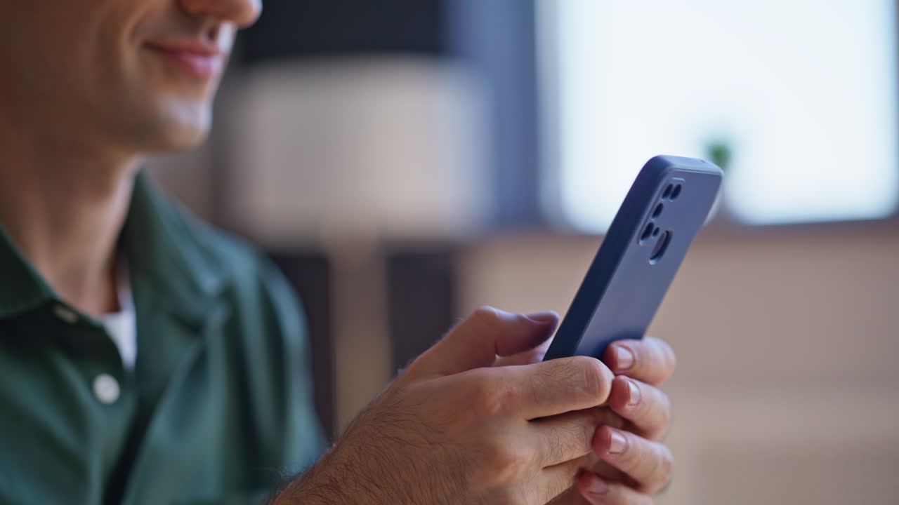 Portrait man typing sms on cellphone at apartment. Smiling businessman messaging