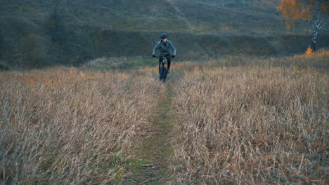 ciclista masculino con casco montando en bicicleta de montaña por la carretera en el campo 1