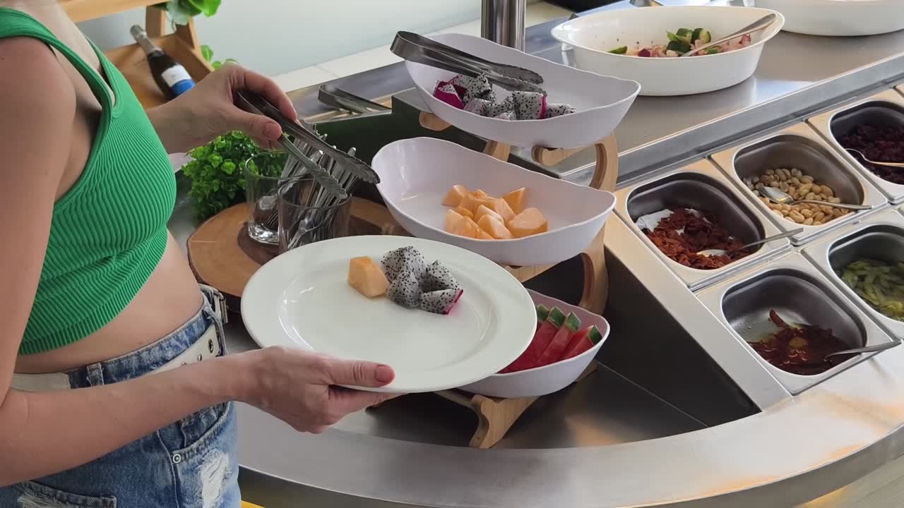 mujer que se sirve ensalada de frutas en un buffet