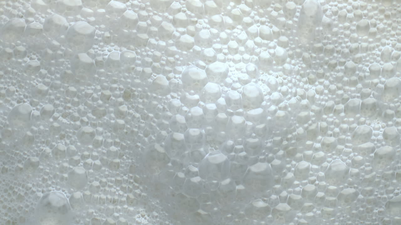 Foamy lactose drink surface top view. Milk liquid frothing texture closeup