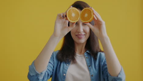 woman holding orange slices in front of her eyes